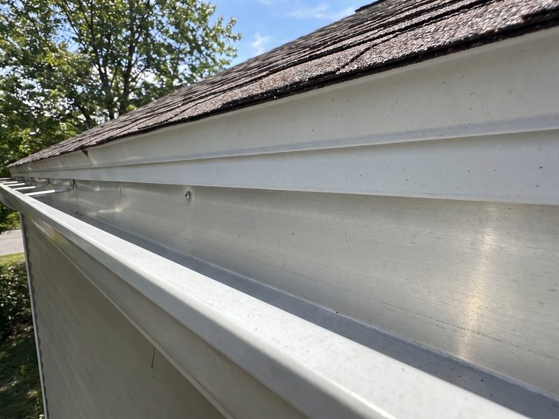 The same rain gutter after cleaning, emptied down to the bare trough with the dark staining washed off the fascia